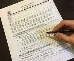 hand filling out application for citizenship